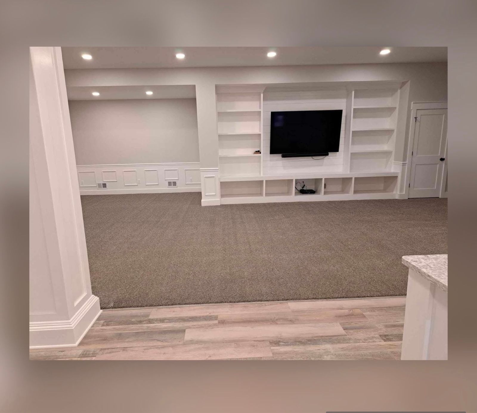 Empty finished basement room with built-in shelves and clean carpet, ready for a move in