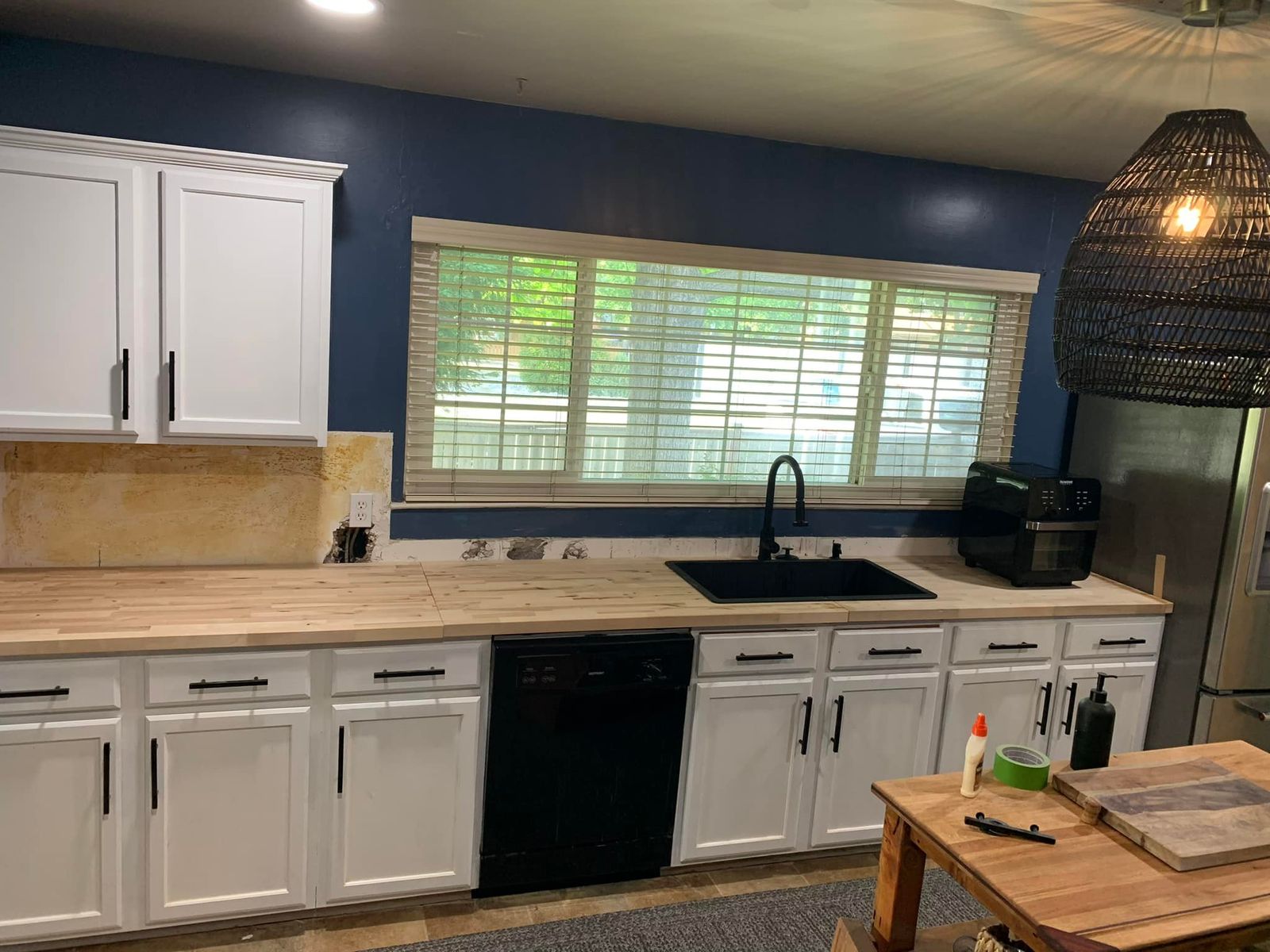 Remodeled kitchen with white cabinets, butcher-block counters and a black sink