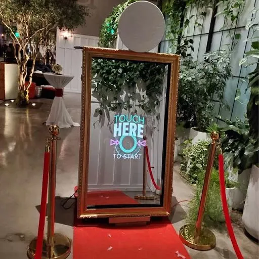 Mirror photo booth framed in greenery with a red carpet