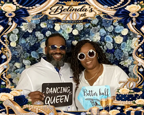 Couple with Dancing Queen props in front of a floral backdrop