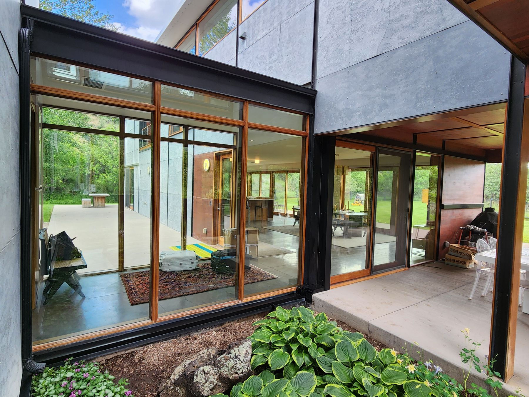 Glass-walled home near Aspen with hostas in the foreground and line hide concealed in the steel frame