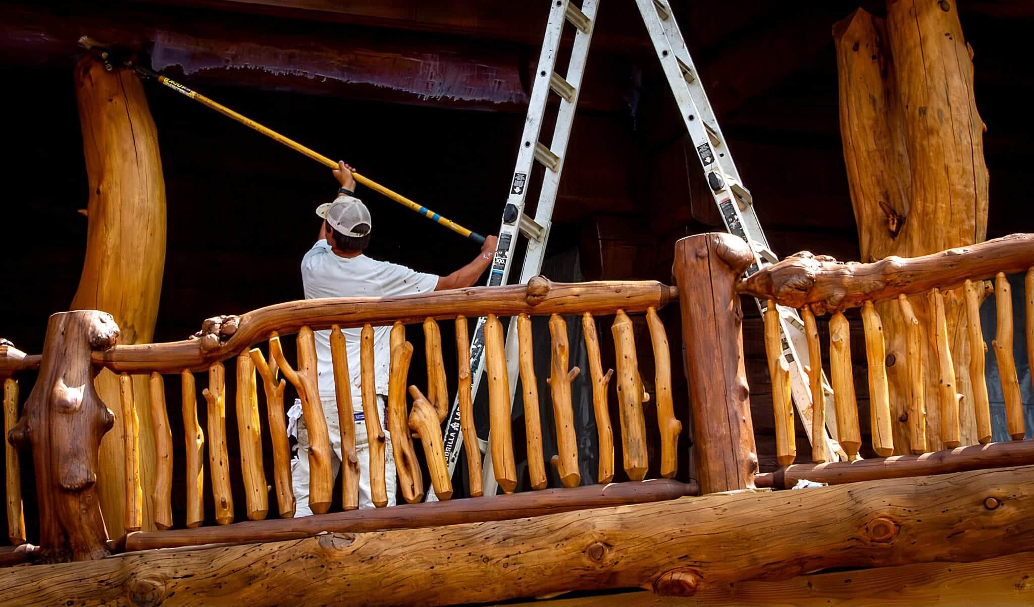 Chewelah Painting crew member staining a character log railing