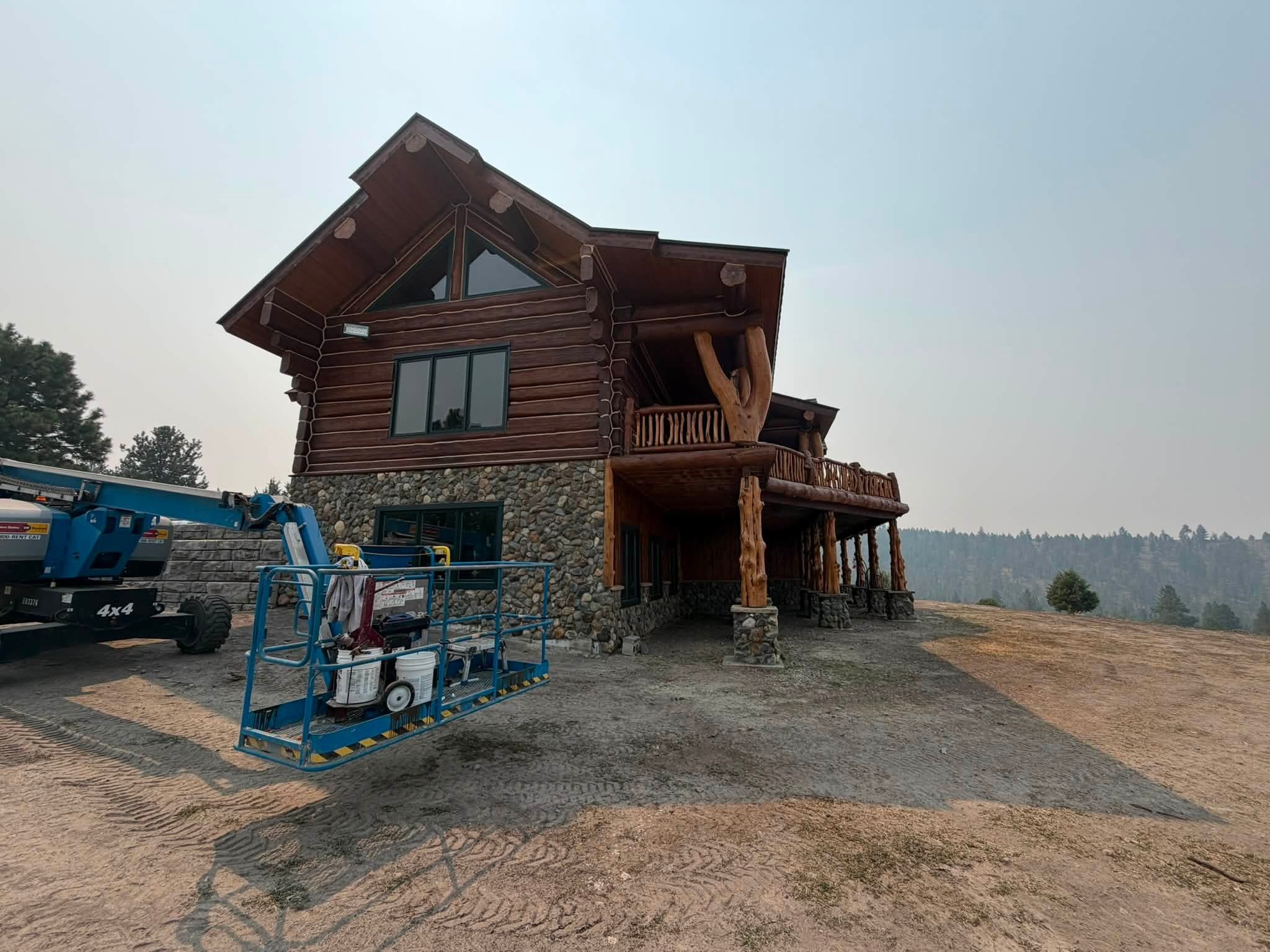 Two storey log home being refinished from a lift in eastern Washington