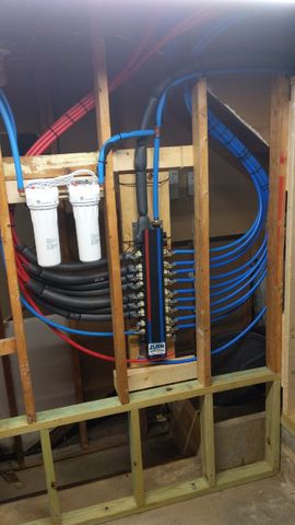 PEX water lines, manifold and filters mounted in a framed basement wall