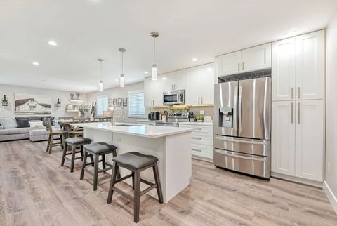 Open kitchen with white shaker cabinets and an island with stools