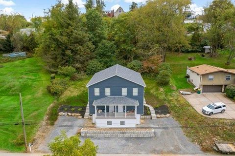 Finished blue-gray home with a white porch from a wide aerial view