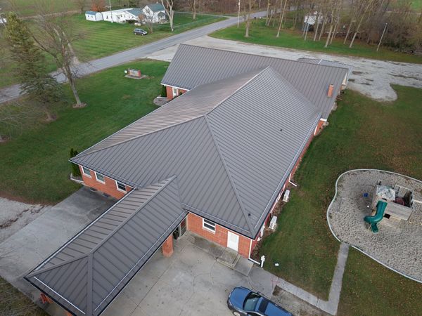 Long grey standing seam roof on a brick building, seen from above