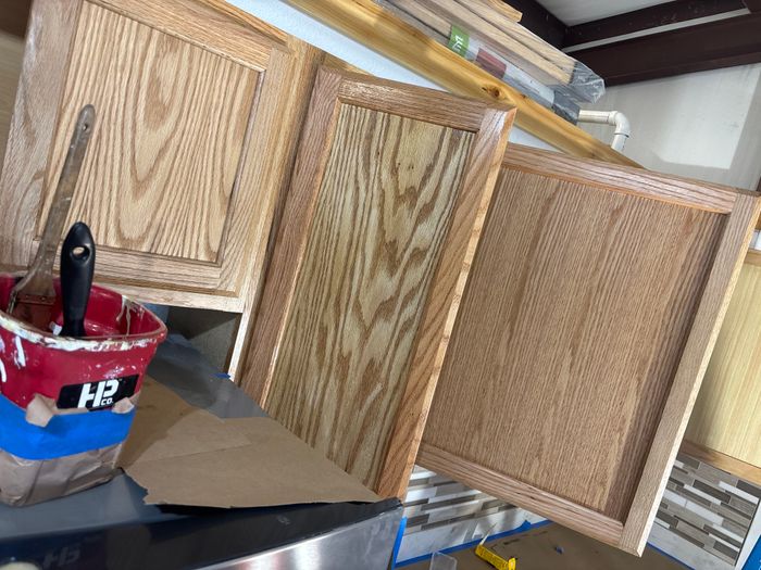 Cabinet doors being refinished on the bench with a brush