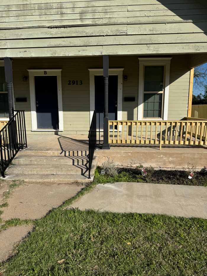 Duplex porch with new wood railing and iron stair rails