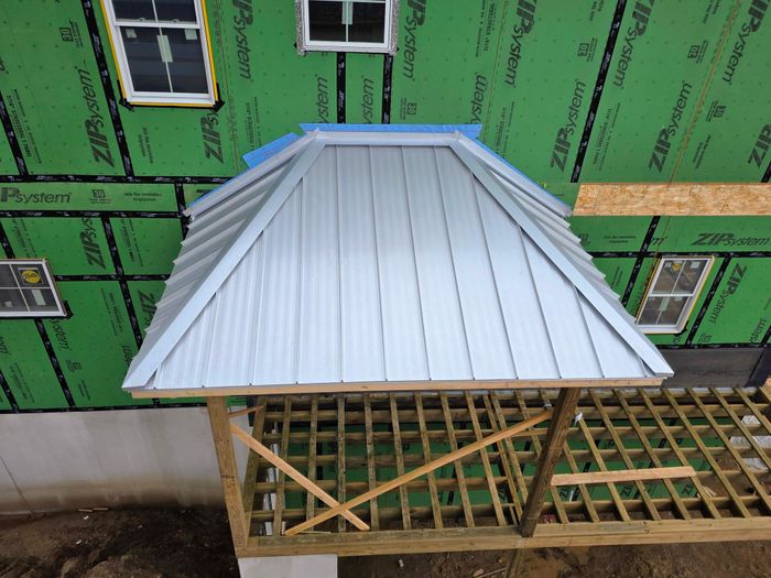 Standing seam panels being installed over open framing on a new build