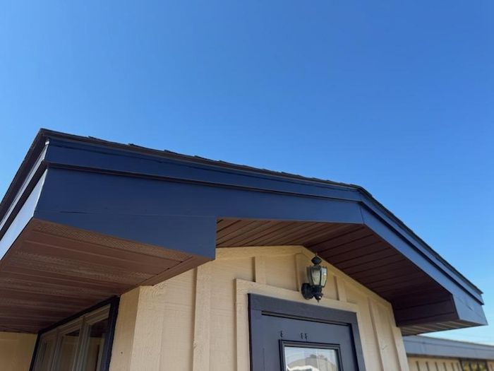 Dark painted fascia and trim over a brown soffit above the front door