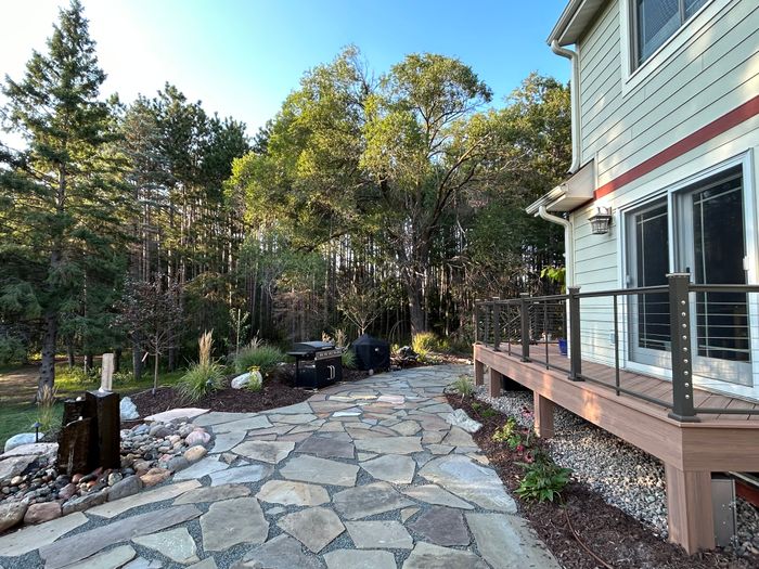 Flagstone patio leading to a deck with cable railing