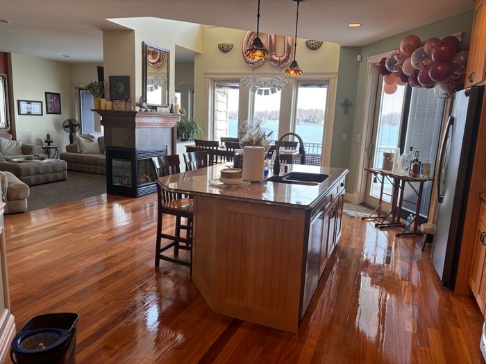 Lake house kitchen island and dining area with polished wood floors