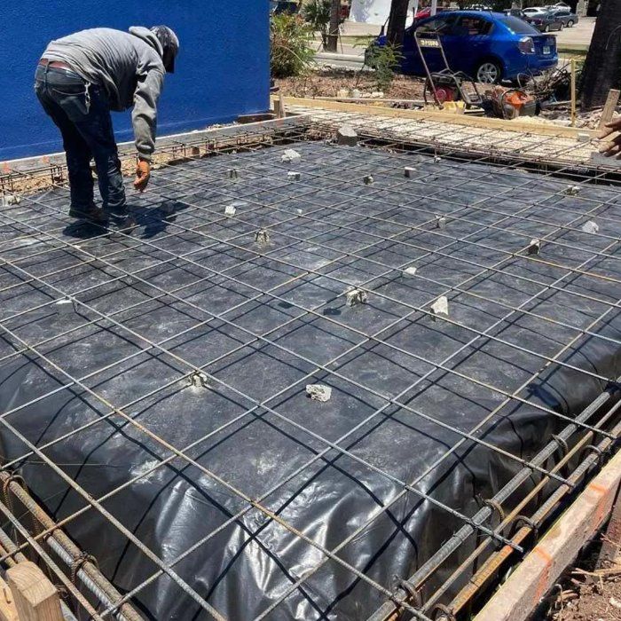 Crew member tying a rebar grid over vapor barrier before a concrete pour