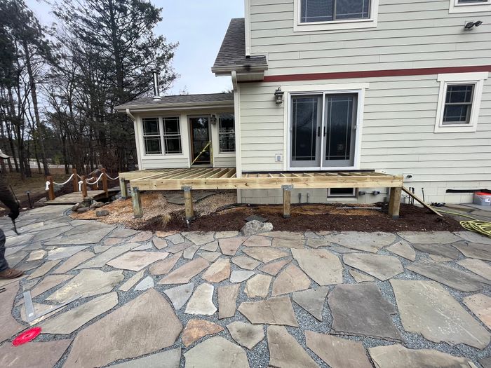 Large flagstone patio laid beside a deck and house