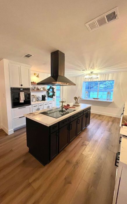 Kitchen remodel with a dark island and stainless range hood