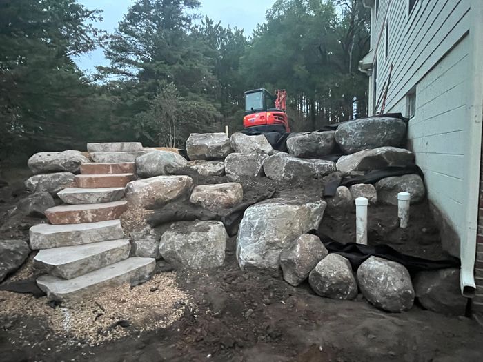Boulder retaining wall with built-in stone steps