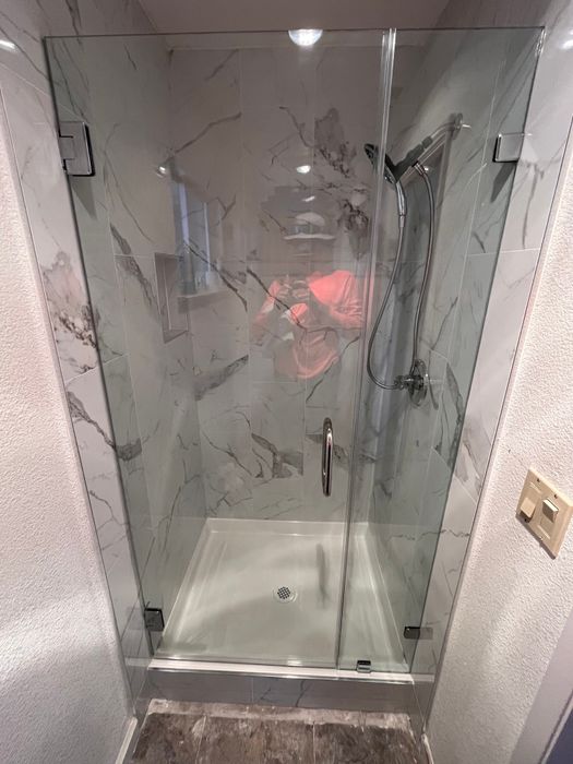 Frameless glass shower enclosure with marble-look tile