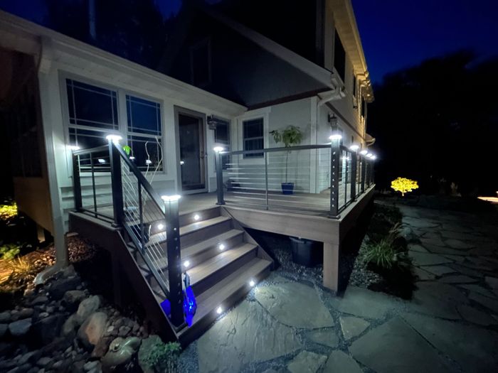 Lit deck stairs and flagstone patio at night