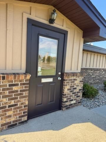 Entry door painted dark brown between brick pillars