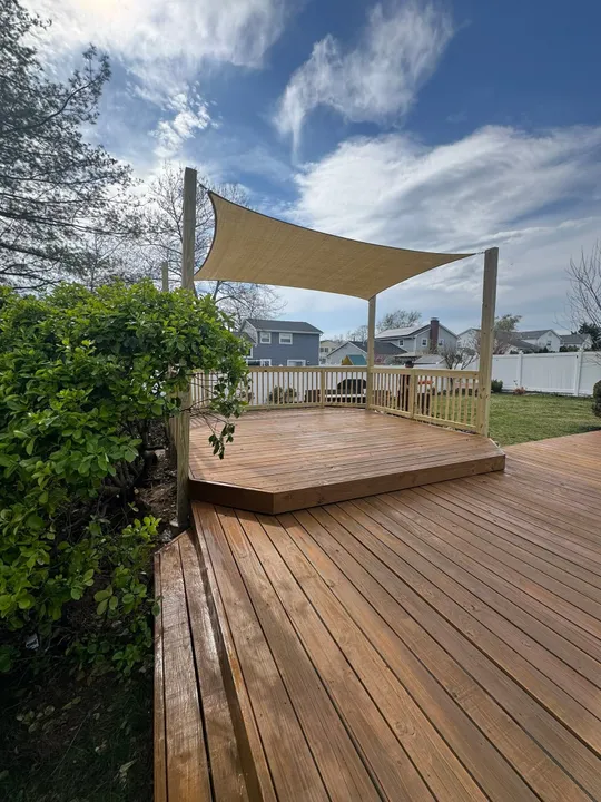 Stained wood deck with new railings and a shade sail