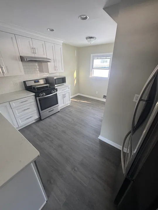 White kitchen with new cabinets, range and vinyl plank floor