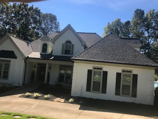 White brick home with a new dark roof and dormer