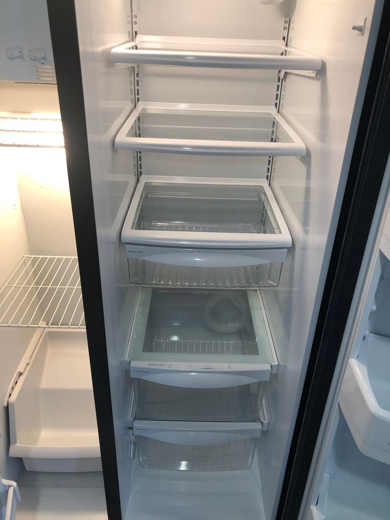 Inside of a refrigerator with clean, empty shelves and drawers