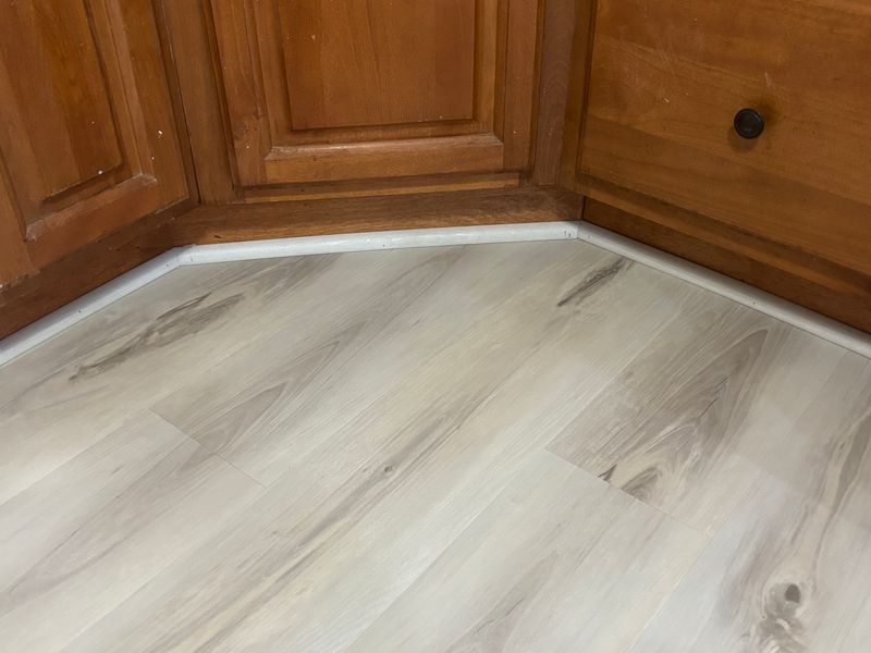 New plank flooring cut along cabinet bases
