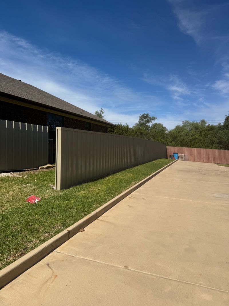 Metal panel fence along a drive