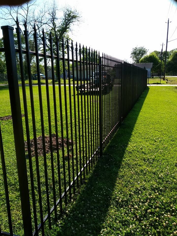 Black picket fence run along a lawn