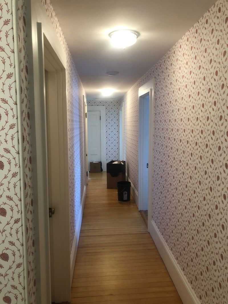 Long upstairs hallway papered in a small red pattern