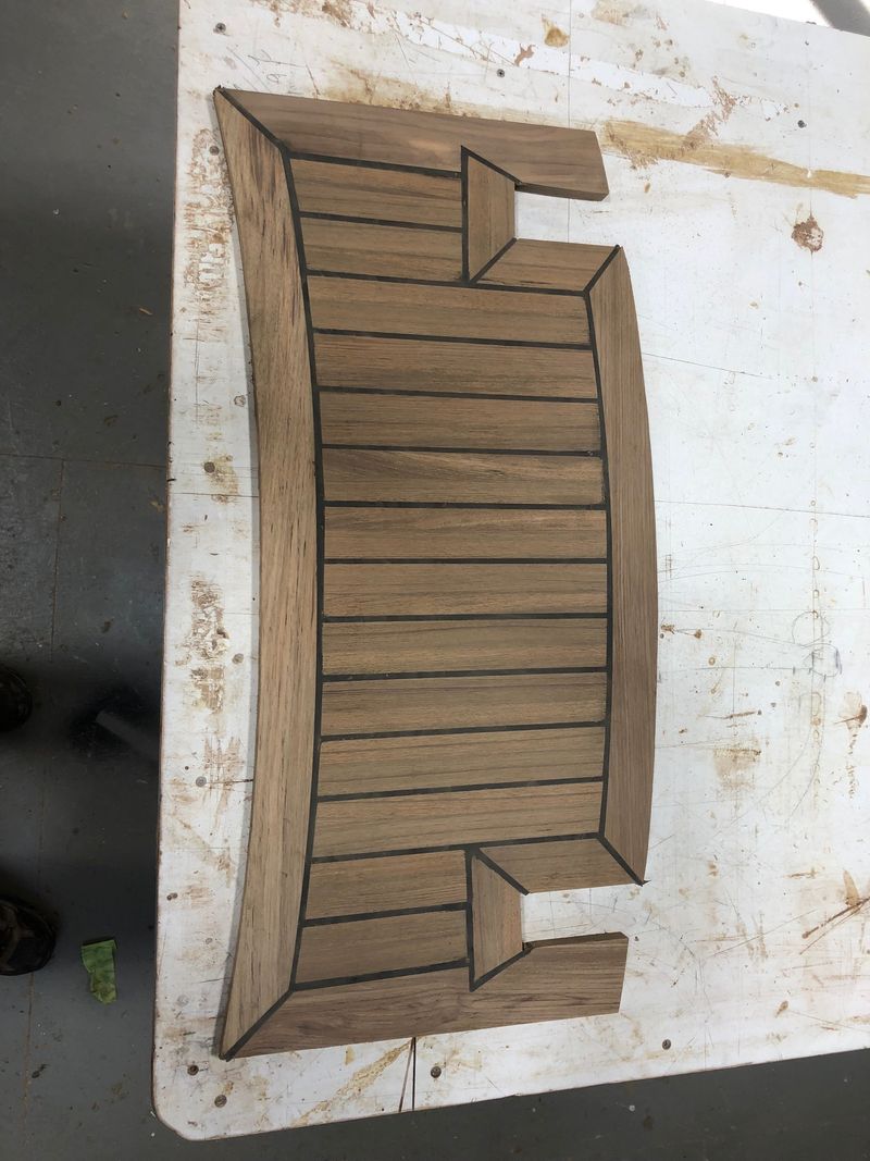 Curved teak grate with dark seams, finished on the bench