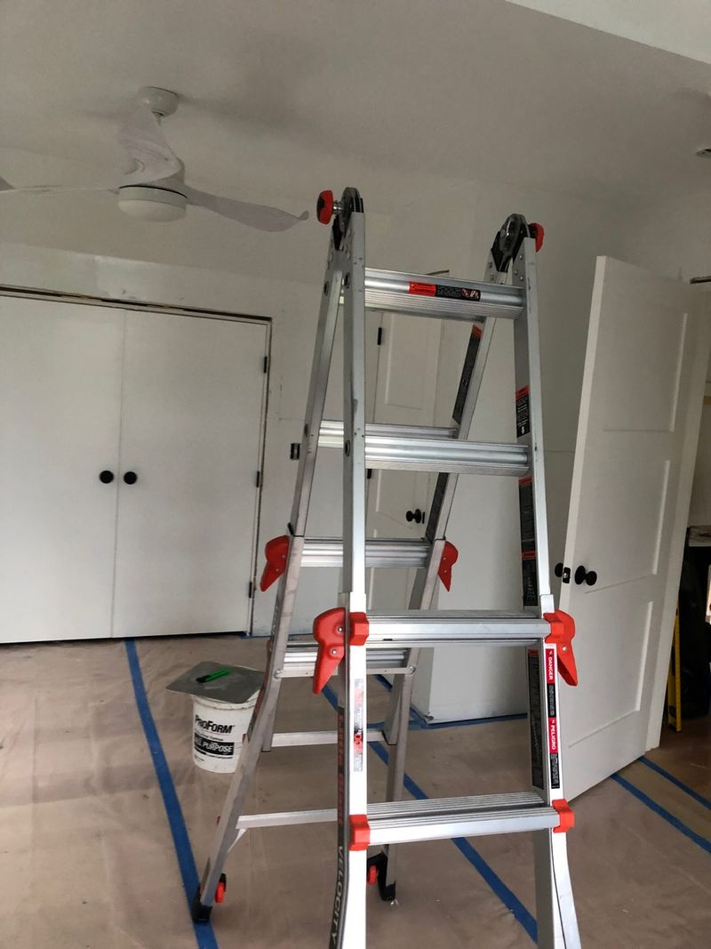 Bedroom floor covered in paper and tape with a ladder ready for work