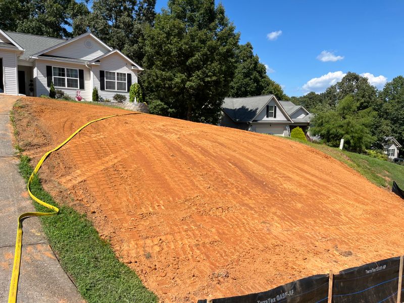 Black silt fence along the bottom of a graded front slope before seeding