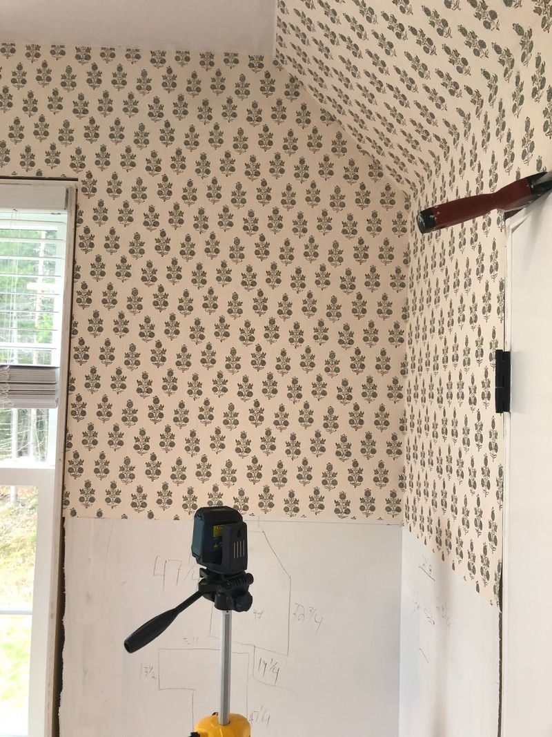 Laser level set up for hanging wallpaper on a sloped wall