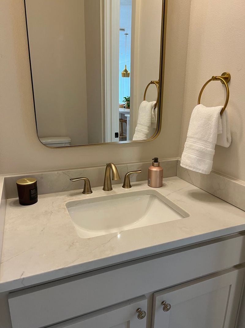 Bathroom vanity with a white marble counter and brass fixtures after a non-toxic clean