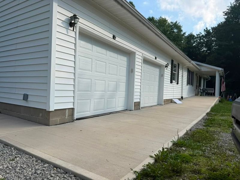 Two white garage doors with new concrete driveway