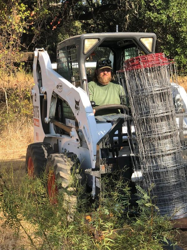 Bighorn Bros Construction crew setting fence posts with a skid steer