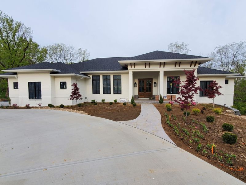 Long, low brick home finished in white with a curved driveway