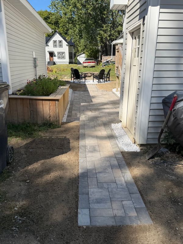 Finished paver walkway running between the house and a raised timber bed