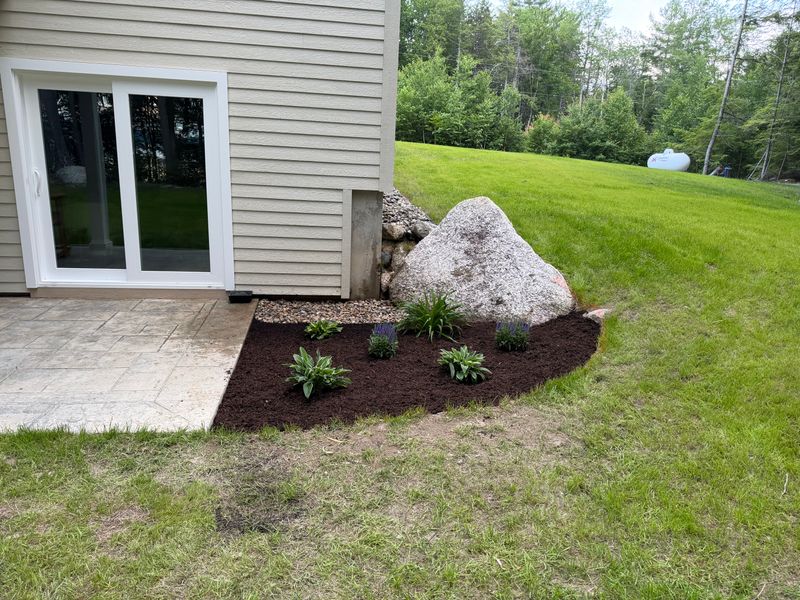 New planting bed with dark mulch and a boulder set as a feature