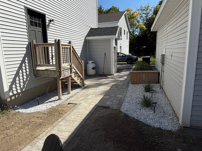 Paver walkway run up to the deck steps with the gravel base still open alongside