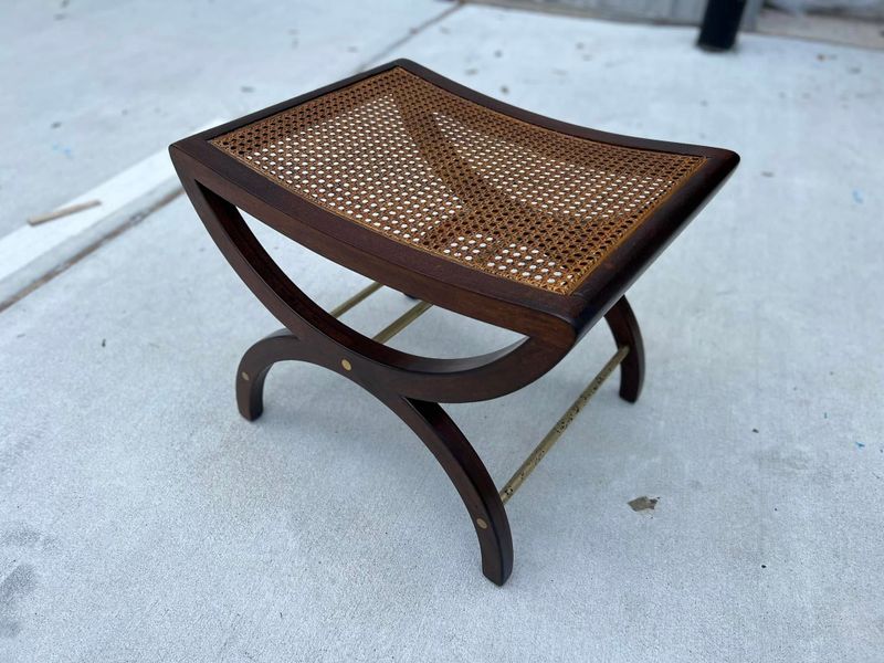 Curved wooden bench with a woven cane seat