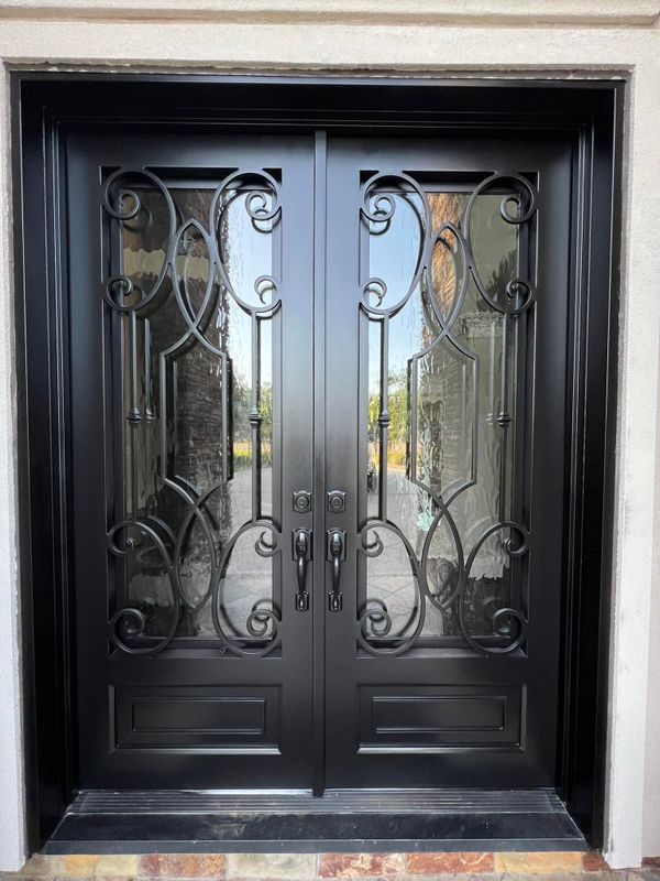 Black double front door with scrolled ironwork over textured glass panels