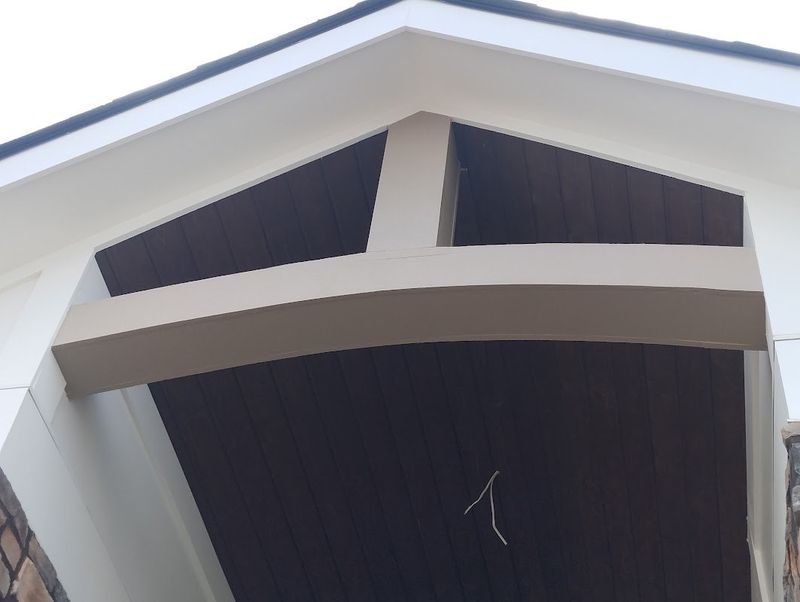 Gable peak with crisp white trim and dark siding after painting