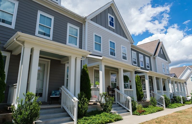 Row of porches with white columns and railings on freshly painted townhomes