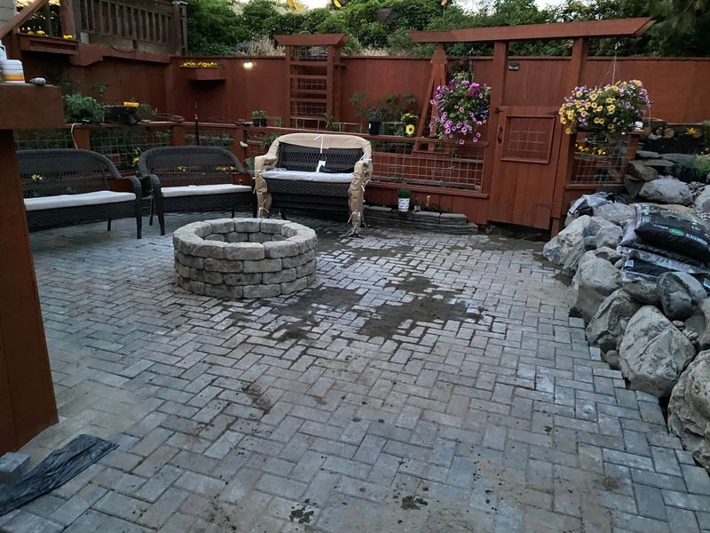 Finished paver patio with a fire pit, outdoor sofa and boulder water feature