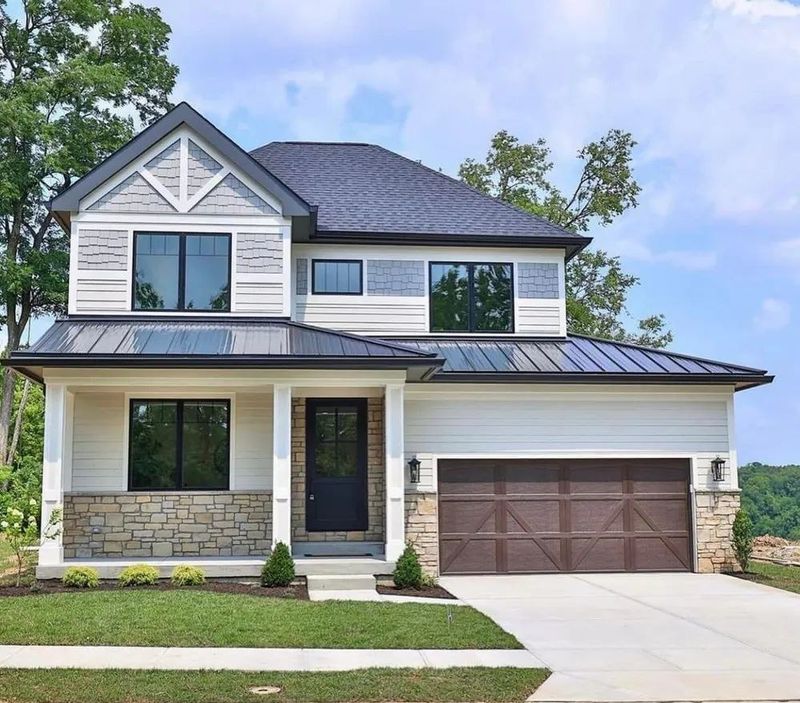New two-story home with gray siding, stone base and brown garage door
