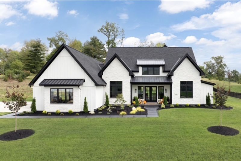 Modern farmhouse with white brick walls, a black roof and a landscaped front lawn
